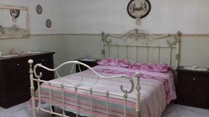 Ein Schlafzimmer mit einem Bett, einem Schminktisch, einem Nachttisch und einer Wanduhr.