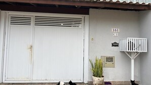 A white garage door with a vent, a potted plant, and a white security gate.