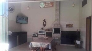 A dining area with a brick fireplace, a television mounted on the wall, and a table with a tablecloth.