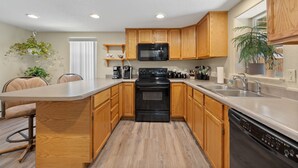 A modern kitchen with wooden cabinets, a black stove, and a dishwasher.