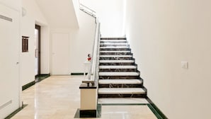 Un escalier moderne avec des marches en marbre et une rampe, menant à l’étage supérieur.
