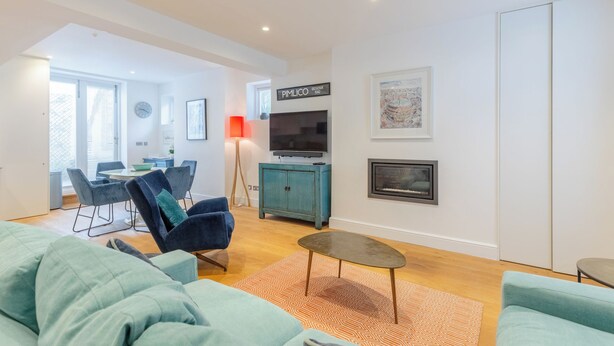 A modern living room with a sofa, a coffee table, a television, and a cabinet.