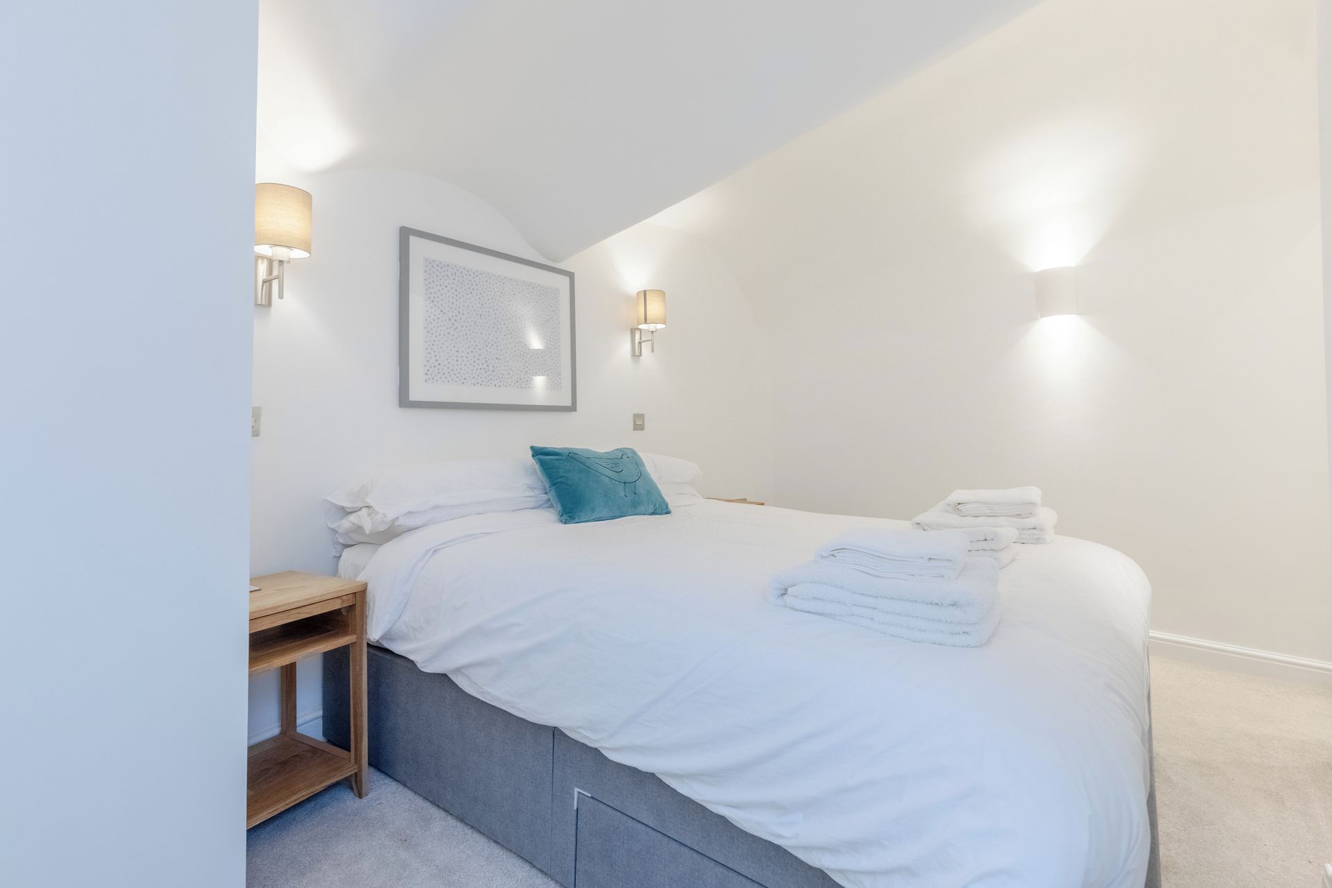 Ein Schlafzimmer mit einem Bett, Nachttischen und Wandleuchten.