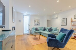 A modern living room with a sectional sofa, a blue armchair, a coffee table, and a TV.