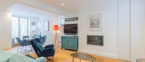 Una sala de estar moderna con un sofá, una mesa de centro, un televisor y un armario.