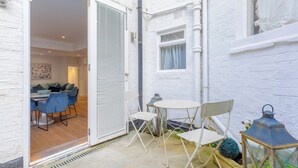 A white brick exterior with a door leading to an interior dining area with blue chairs and a table.
