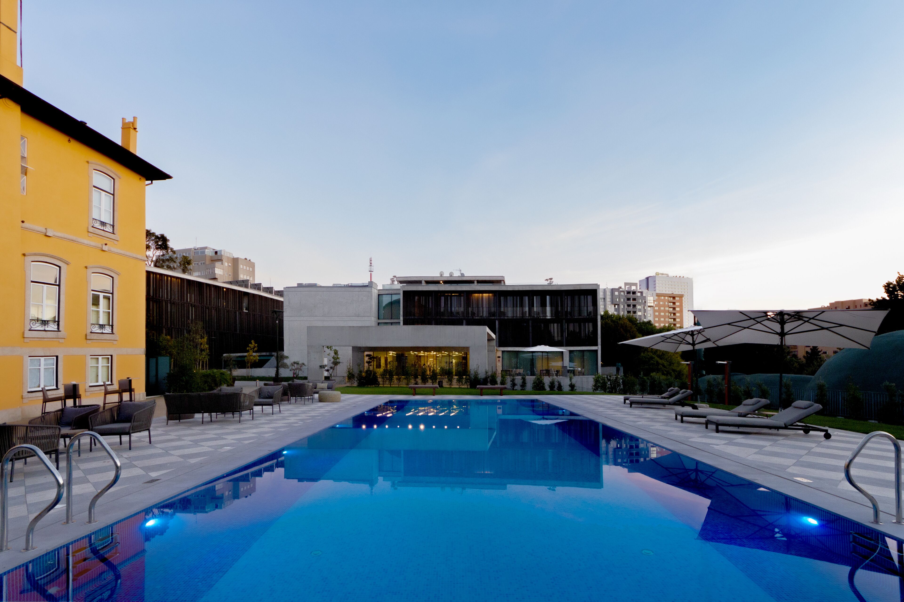 Une piscine avec des chaises longues et un bâtiment moderne en arrière-plan.