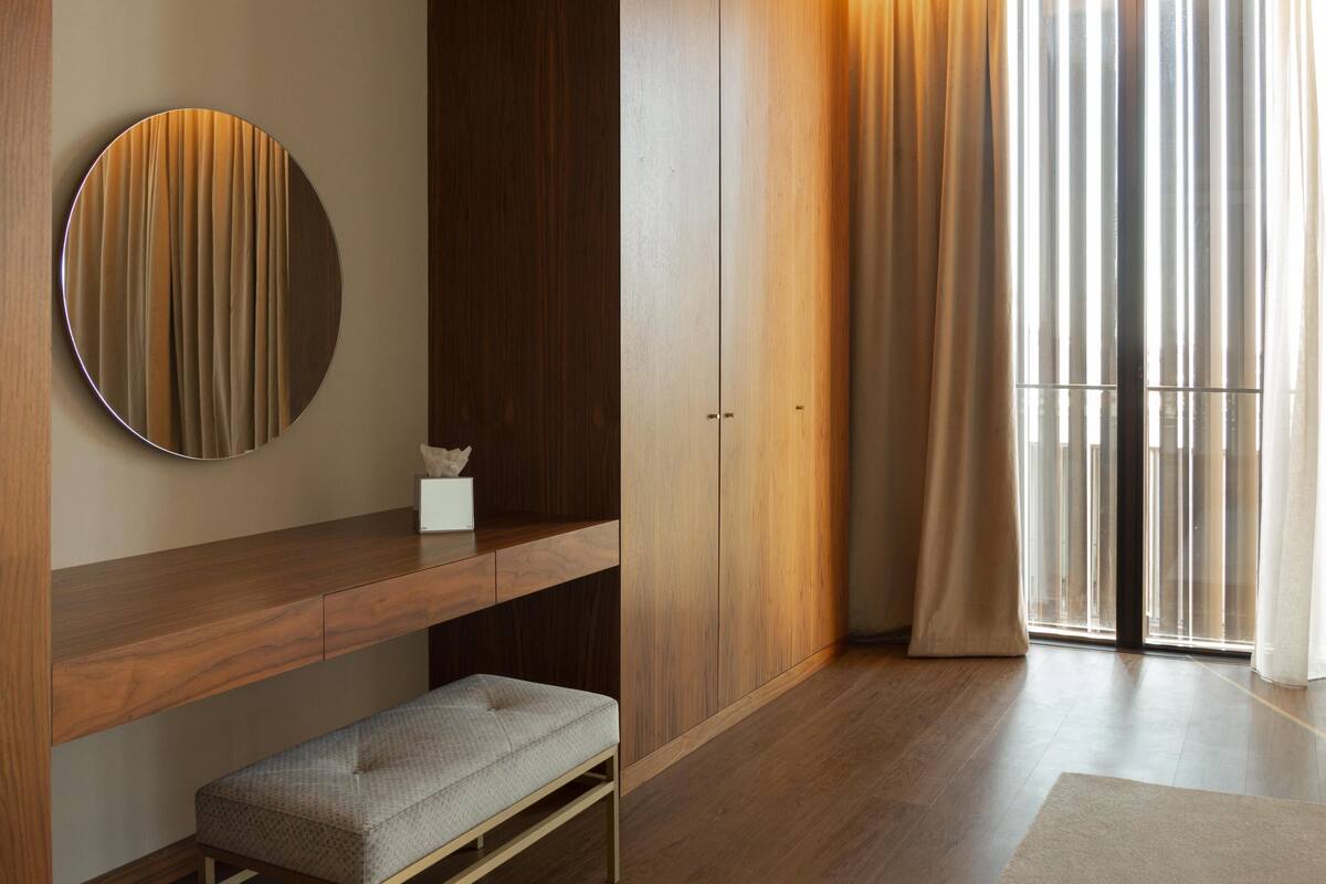 A modern room with a wooden bench, a round mirror, and a built-in wardrobe.