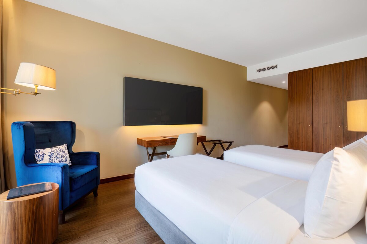 Une chambre d’hôtel avec un lit, un bureau, une chaise et un téléviseur.