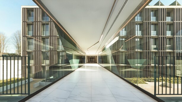 Un edificio moderno con fachada de vidrio, un pasillo central y piso de baldosas.