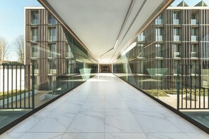 Un edificio moderno con fachada de vidrio, un pasillo central y piso de baldosas.