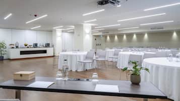 Une salle de conférence équipée de tables rondes, de chaises et d’un coin café.