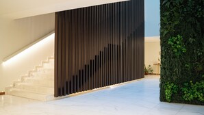 Una escalera moderna con un panel de madera y una pared verde con plantas.
