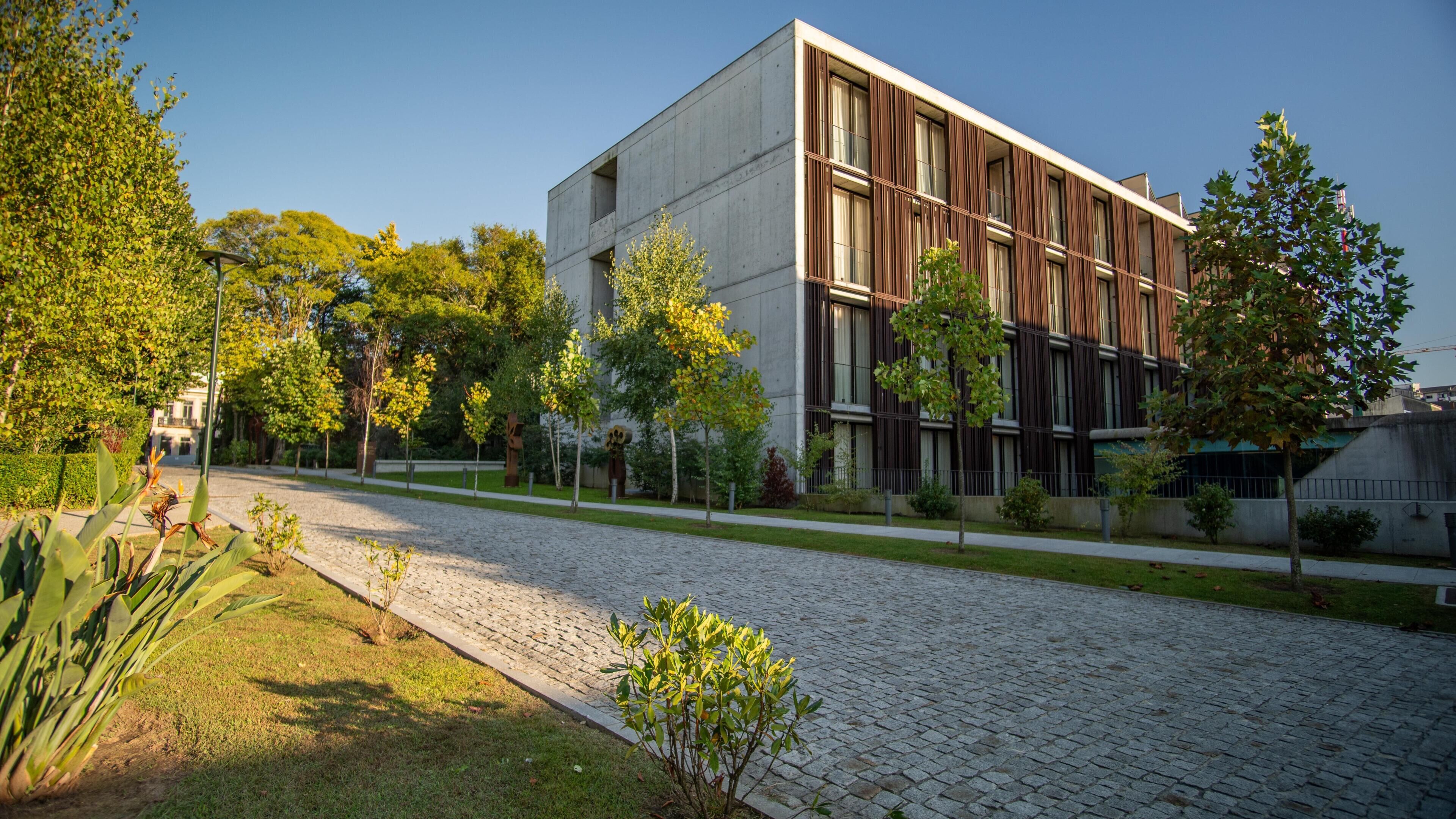 Um edifício moderno com telhado plano, janelas amplas e um pátio pavimentado.