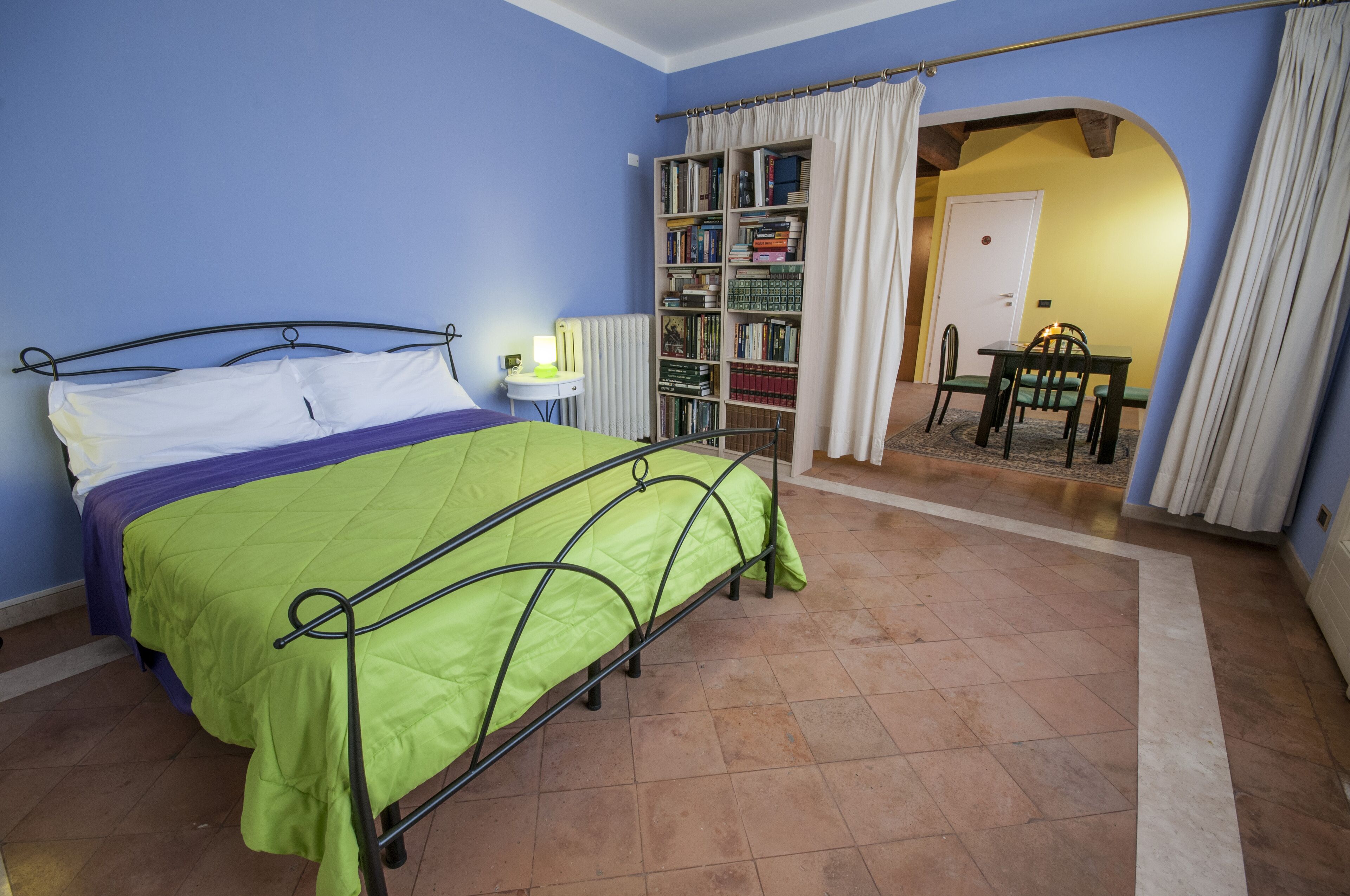 Ein Schlafzimmer mit einem Bett, einem Nachttisch, einem Bücherregal und einem kleinen Tisch mit Stühlen.