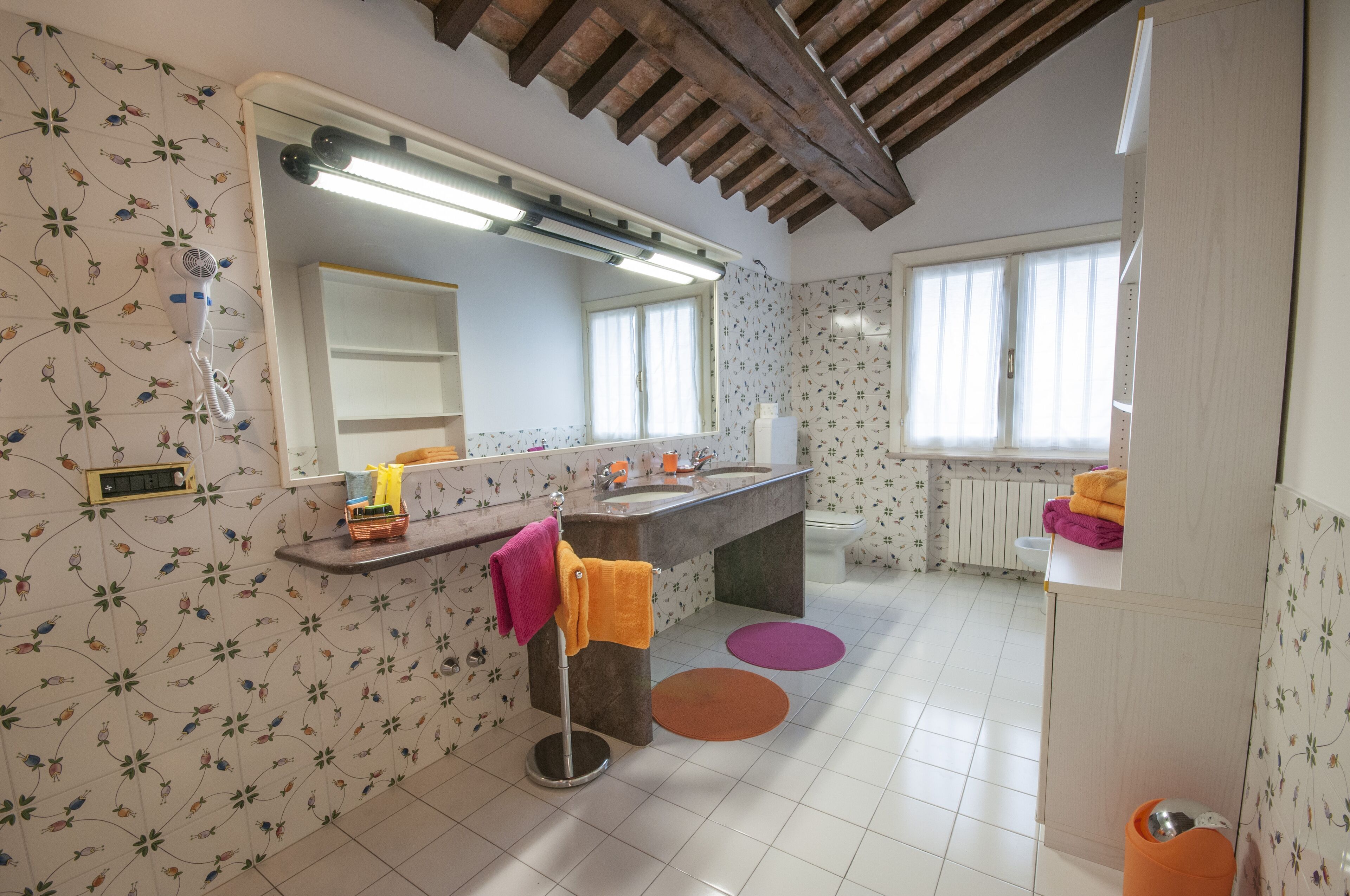 A bathroom with a large mirror, a sink, a toilet, and a shower area.