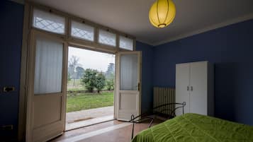 Un dormitorio con cama, armario y ventana con cortinas.