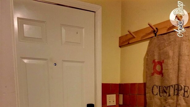 A white door with a black handle, a red-tiled wall, and a hanging bag with text. - Studio Apartment in Historic Neighborhood (Amarillo)