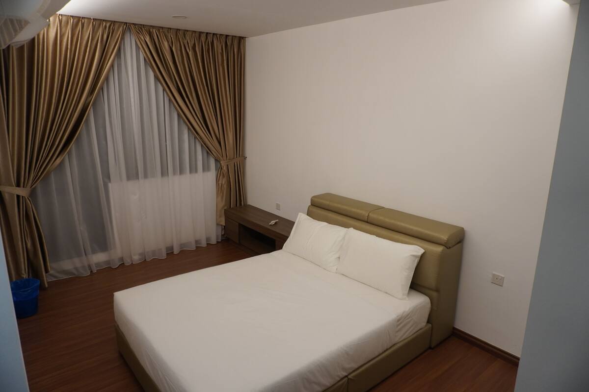 Habitación de hotel con cama, mesita de noche y ventana con cortinas.