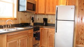 A kitchen with wooden cabinets, a stainless steel refrigerator, a microwave, a stove, and a coffee maker.