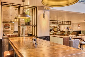 Un área de bar moderna con mostrador de madera, asientos y una estantería visible para vinos.