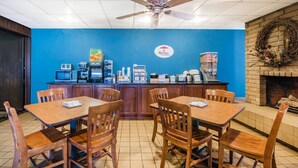 Un espace réservé au petit-déjeuner, avec des tables et des chaises en bois, une machine à café et un four à micro-ondes sur le comptoir.