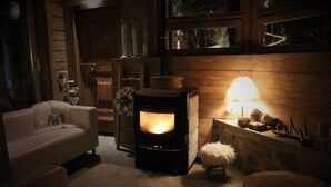 A cozy room with a wood-burning stove, a white sofa, and a fluffy rug. - B&B Ca' Virò (Albosaggia)