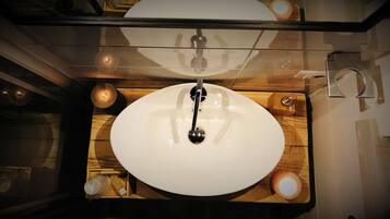 Ein Badezimmer mit einem weißen Waschbecken, einer Holzauskleidung und einer Duschkabine aus Glas.