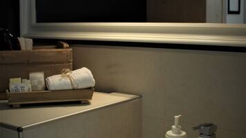 A bathroom with a white sink, a bottle of hand soap, and a wooden tray with towels.