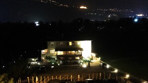 A building with multiple floors, a parking area with cars, and a fence in the foreground. - B&B Ca' Virò (Albosaggia)