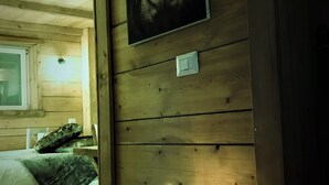 A cozy room with wooden walls, a bed with a green blanket, and two lit candles on a small table. - B&B Ca' Virò (Albosaggia)