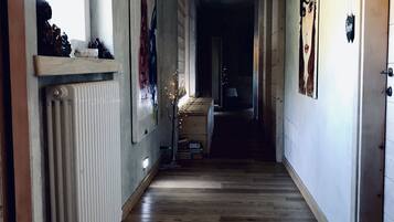 Un pasillo con suelo de madera, un radiador y una estantería con adornos.