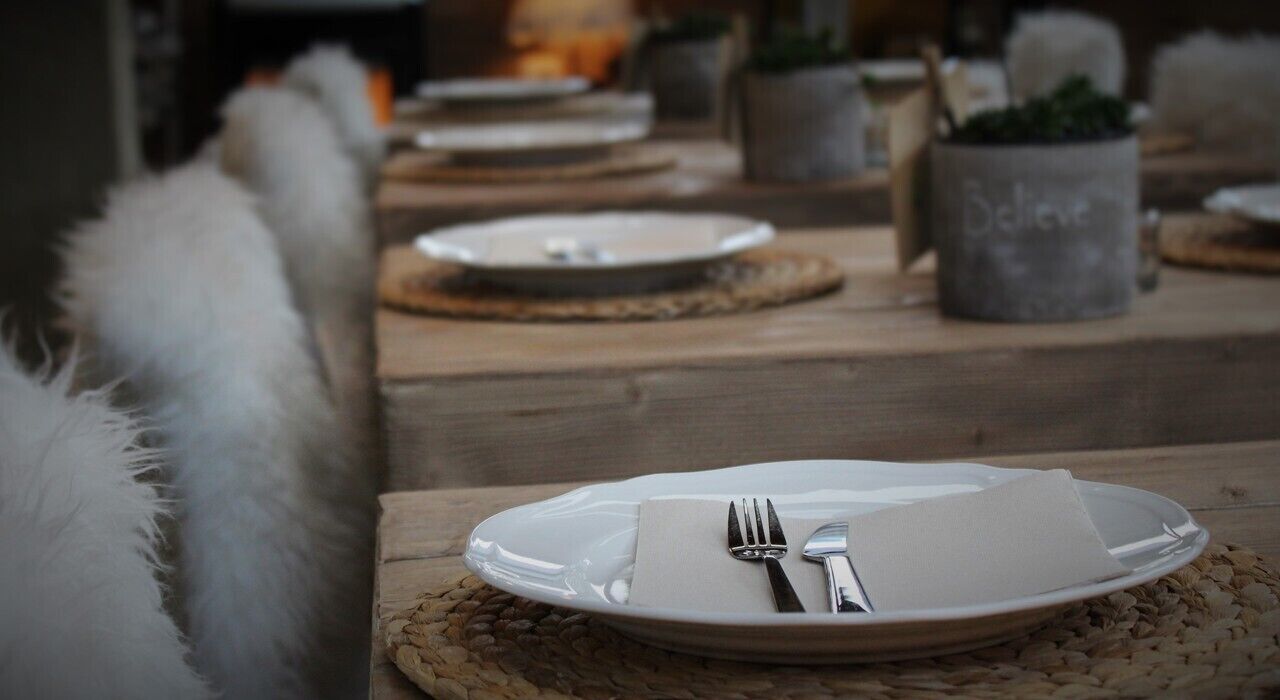 Une table à manger dressée avec une assiette blanche, des couverts et une serviette.