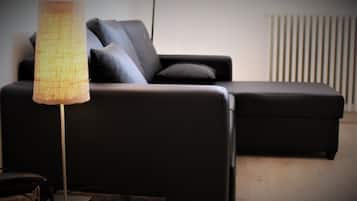 Una sala moderna con un sofá negro, una lámpara de pie y un radiador.