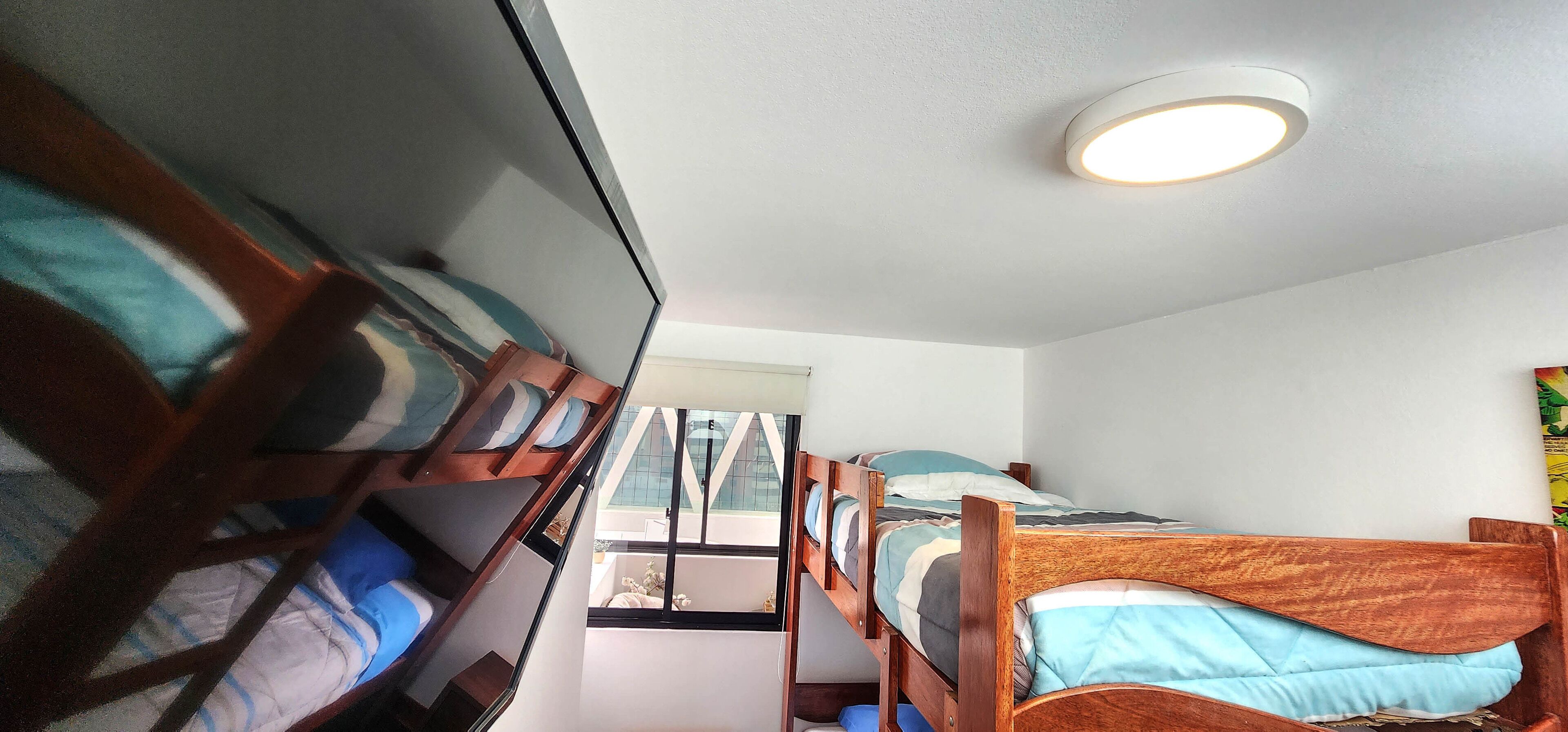 Ein Schlafsaalzimmer mit Etagenbetten, einem Fenster und einer Deckenleuchte.