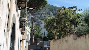 A narrow street with buildings on one side and a mountain in the background.