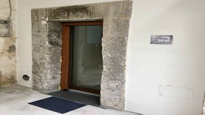 A doorway with a stone frame and a wooden door, a small mat at the entrance, and a sign on the wall.