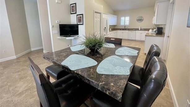 A dining area with a marble table, black chairs, and a potted plant.