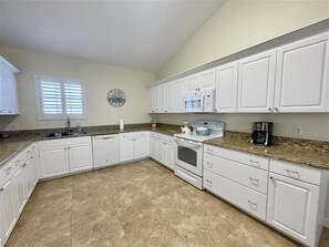 A kitchen with white cabinets, a granite countertop, a built-in oven, and a microwave. - Beach Bird House- Walk to the Beach! 4224 Oriole (Wilbur by the Sea)