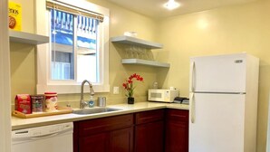 A kitchen with a dishwasher, red cabinets, a white refrigerator, a microwave, and a window with blinds. - Modern and Perfect Self Contained 4B/2BA Home +  Parking + BART (El Cerrito)