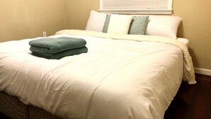 A neatly made bed with a white comforter and two pillows, one green and one white. - Modern and Perfect Self Contained 4B/2BA Home +  Parking + BART (El Cerrito)