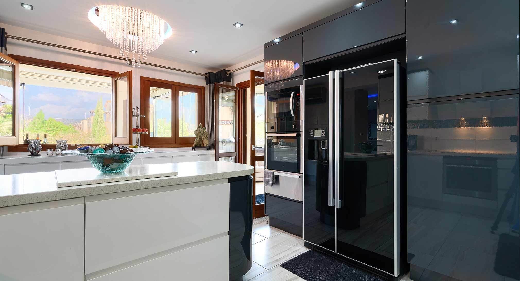 Una cocina moderna con una isla grande, un refrigerador con puerta de vidrio y un candelabro.