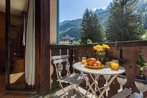 Un balcón con una mesa dispuesta para el desayuno, una silla y vistas a las montañas.
