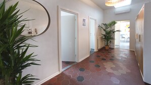 A hallway with a geometric patterned floor, a round mirror, and a potted plant.