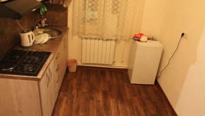 A small kitchen with a stove, sink, and a refrigerator.