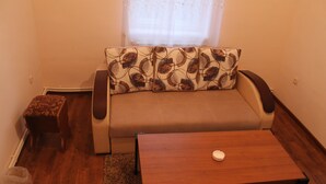 A living room with a sofa, a wooden coffee table, and a small wooden stool.