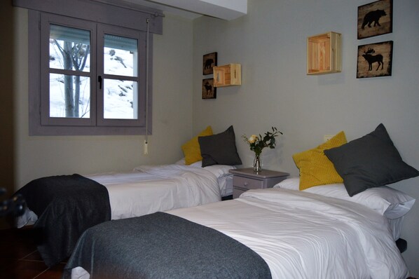 A bedroom with two beds, a nightstand, and a window with blinds. - The Hostel (Monachil)