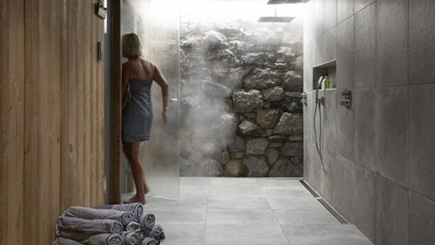 A spa area with a stone wall, a towel rack, and a shower area. - B&B Chalet Nono (Montriond)