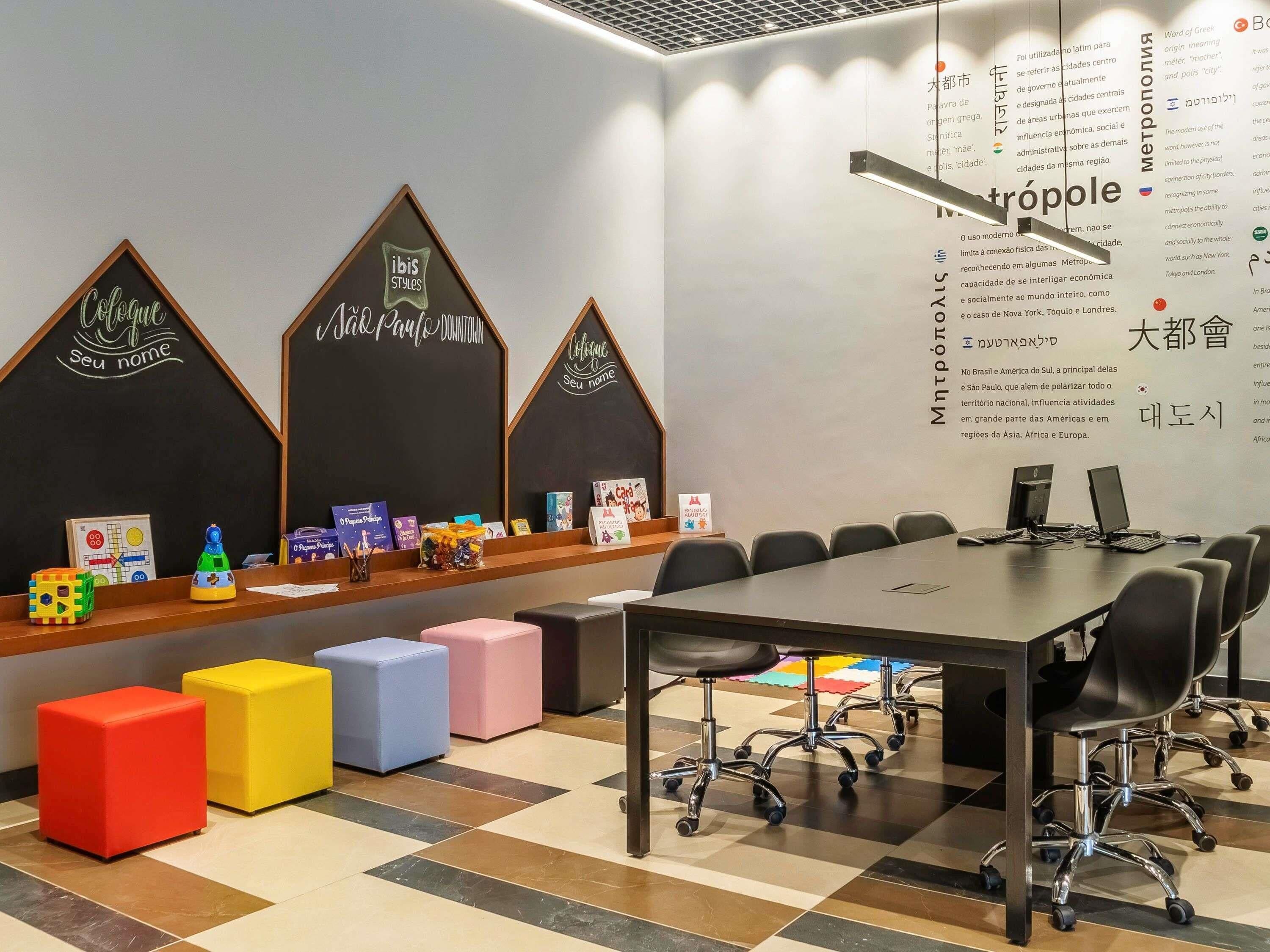 Un salón de conferencias con una larga mesa, múltiples sillas y taburetes coloridos.