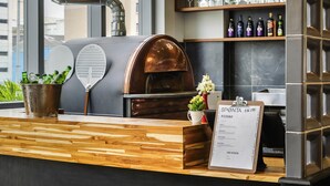 Een keukenblad met een pizzaoven, een menukaartstandaard en een raam met uitzicht op gebouwen.